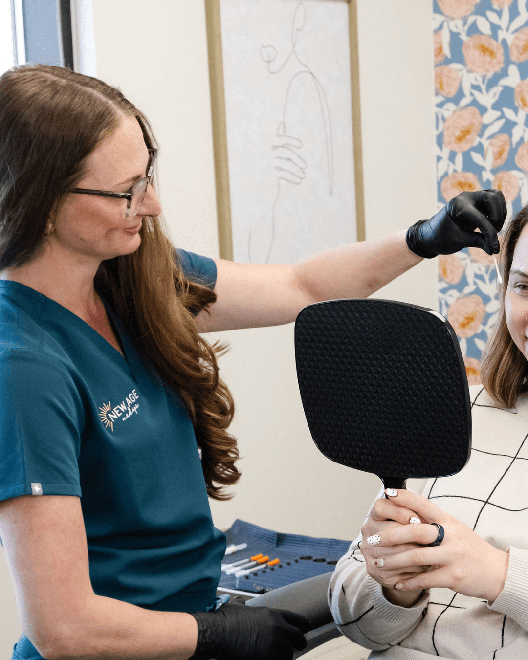 Brie Freckleton, AGACNP reviewing treatment goals with a client in the mirror at New Age Medspa