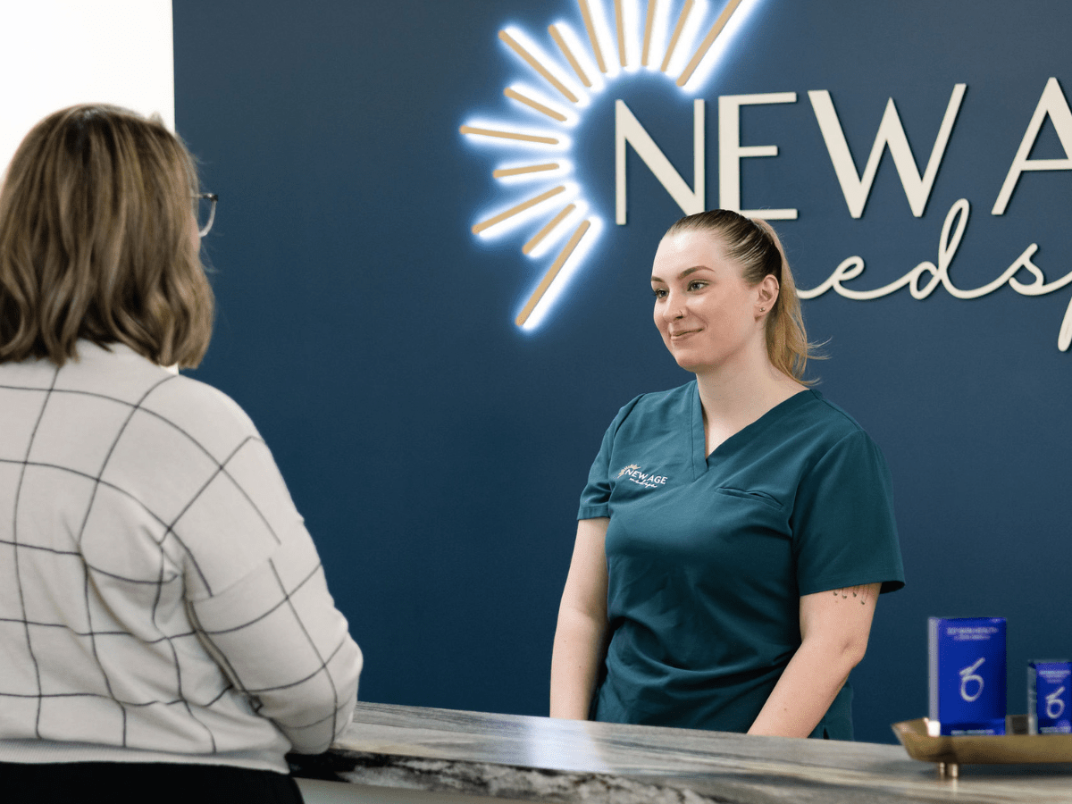 Kassidy O'Connell welcoming a guest at the New Age Medspa reception desk during the First Thursday social